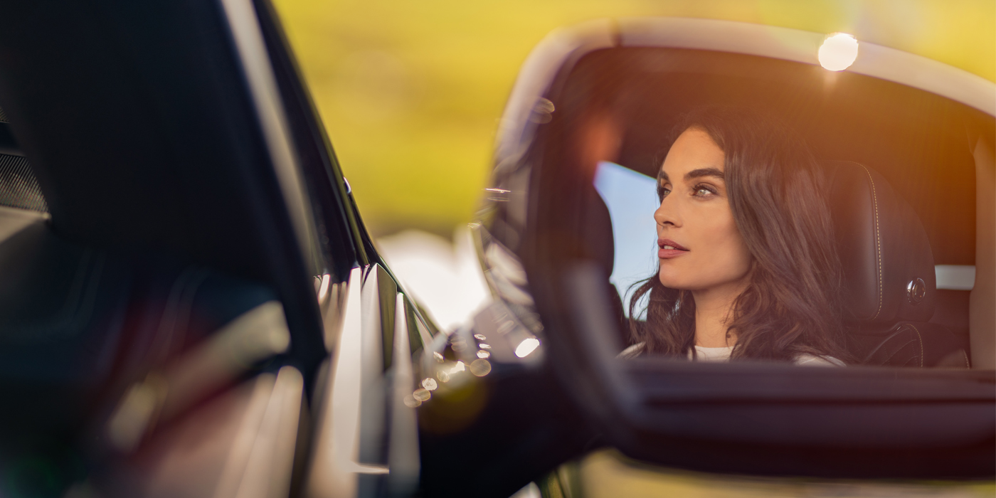 Gohm Sportwagen GmbH | Bentley Singen profile of dark haired woman's face in mirror of Bentley car in sunlight
