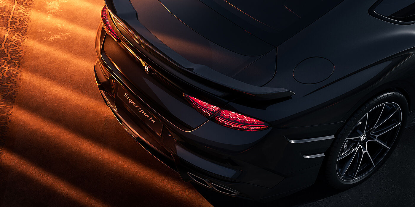 Gohm Sportwagen GmbH | Bentley Singen Bentley Supersports rear overhead view showing illuminated rear lamps and Supersports Forged Alloy wheel in Anthracite paint against a dark grey and red background