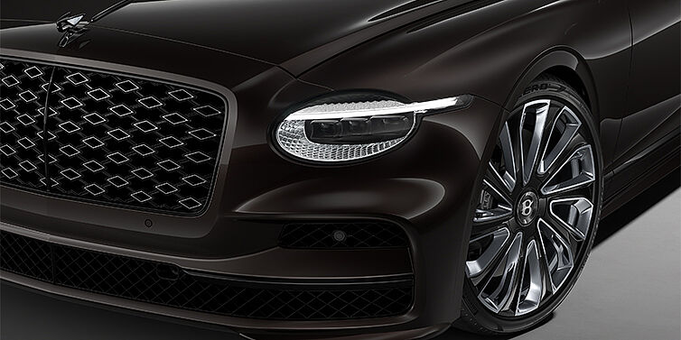Gohm Sportwagen GmbH | Bentley Singen New Bentley Flying Spur Mulliner sedan head lamp against Havana brown paint with 22" Mulliner Black Painted & Polished wheel
