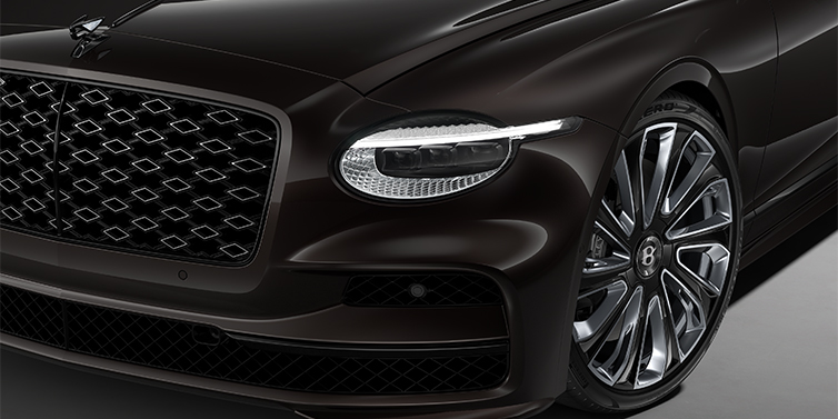 Gohm Sportwagen GmbH | Bentley Singen New Bentley Flying Spur Mulliner sedan head lamp against Havana brown paint with 22" Mulliner Black Painted & Polished wheel
