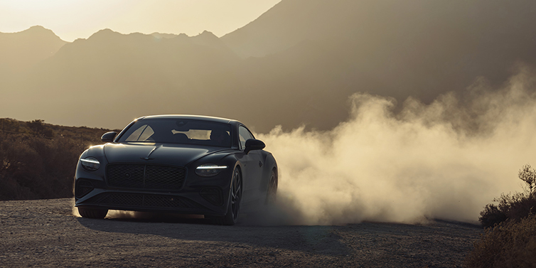 Gohm Sportwagen GmbH | Bentley Singen Bentley Continental GT coupe in Thunder paint front 3/4 driving with dust trail at sunset