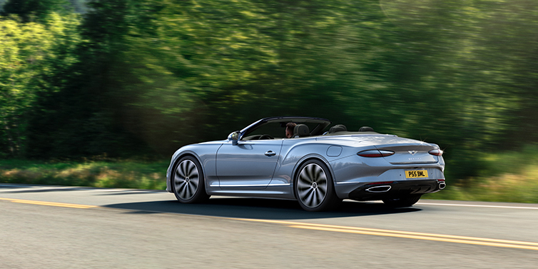 Gohm Sportwagen GmbH | Bentley Singen New Bentley Continental GTC convertible side view in Silverlake paint with 22 inch ten spoke wheels driving dynamically on a country road